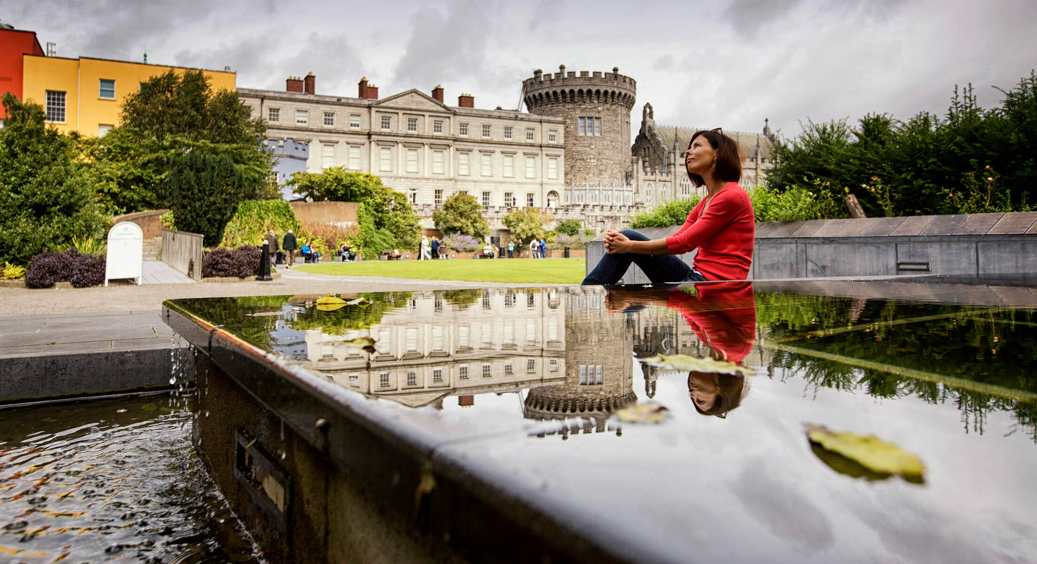 a woman sitting on a ledge in front of a castle